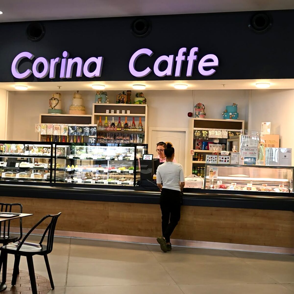 Interiorul unei locații Corina Caffe, cu firma luminoasă și tejgheaua lungă cu vitrine